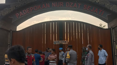 Warga dan petugas kepolisian saat berada di depan gerbang padepokan.