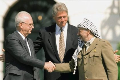Perdana Menteri Israel Yitzhak Rabin (kiri) dan Ketua Organisasi Pembebasan Palestina Yasser Arafat (kanan) berjabat tangan di Gedung Putih di hadapan Presiden Bill Clinton pada bulan September 1993. (Getty Images)